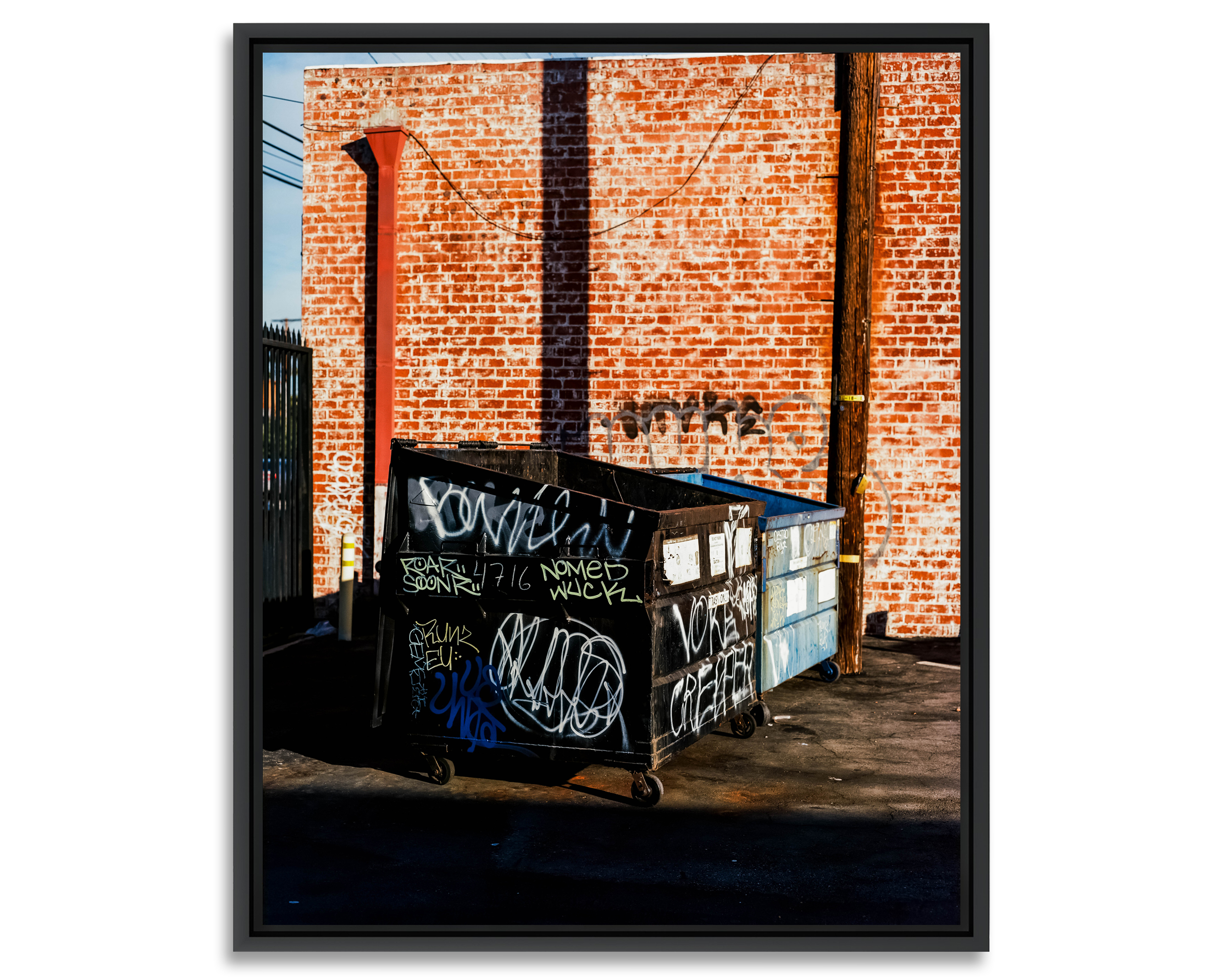 Bins Deux bennes à ordures taguées devant un mur en briques rouges.