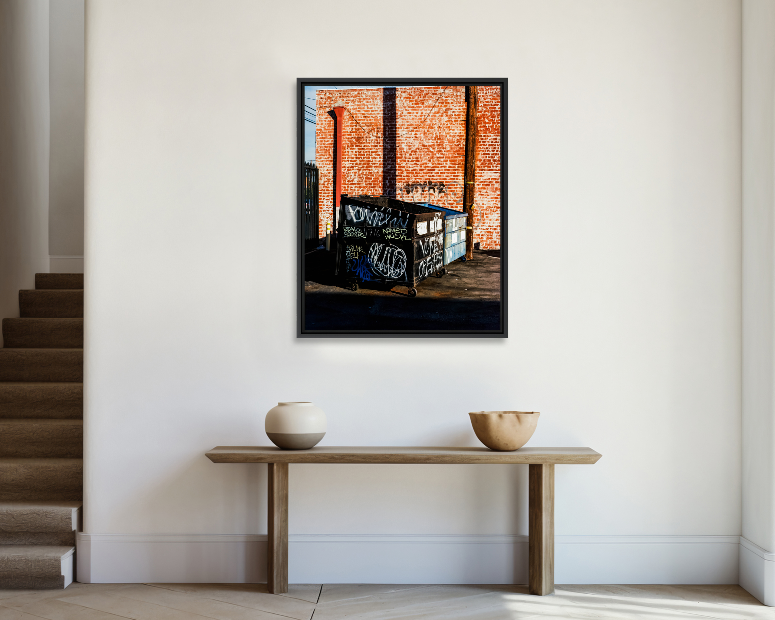 BINS Deux bennes à ordures taguées devant un mur en briques rouges.